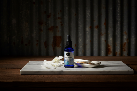 Blue bottle with dropper on a marble slab against a rustic metal curtain background