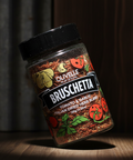 Jar of Olivelle Bruschetta seasoning on a wooden surface with a dark background