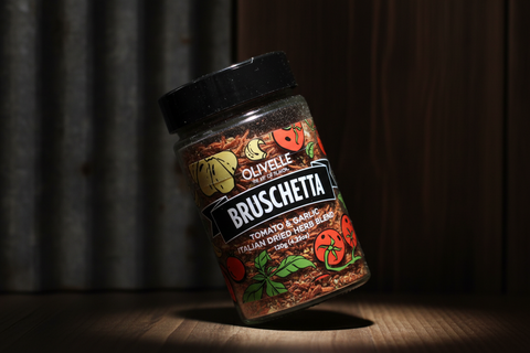 Jar of Olivelle Bruschetta seasoning on a wooden surface with a dark background