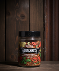Jar of Olivelle Bruschetta Italian Dried Herb Blend on a wooden surface with a wooden background
