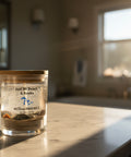 Glass candle jar with wooden lid labeled 'Just MI Beach & Rocks' on a neutral background