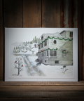 Framed illustration of a snowy house on a wooden surface
