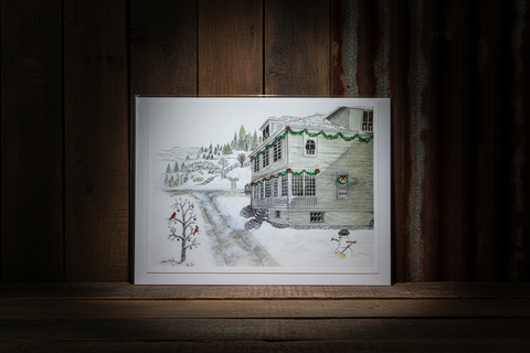 Framed illustration of a snowy house on a wooden surface