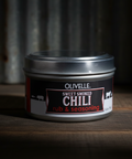 Jar of Olivelle Sweet Smoked Chili Rub & Seasoning on a wooden surface with a dark background