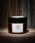 Jar of 'Jessica's Strawberry Tallow' on a wooden surface with a dark background
