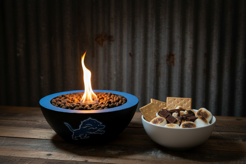 Concrete Detroit Lions bowl with flames and a bowl of s'mores on a wooden surface.