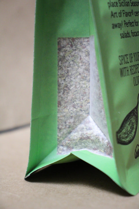 Green package with a clear window showing white contents on a beige background