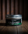 Olivelle Herb & Garlic seasoning container on a wooden surface with a dark background