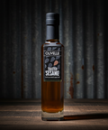 Bottle of Olivelle Toasted Sesame oil on a wooden surface with a dark background