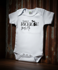White baby onesie with text on a wooden surface