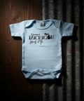 Light blue baby onesie with text on a wooden surface