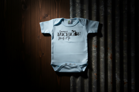 Light blue baby onesie with text on a wooden surface