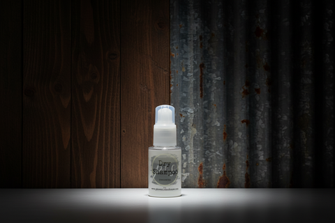 Small white bottle labeled 'Dry Shampoo' on a dark background