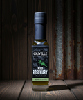 Bottle of Olivelle Wild Rosemary olive oil on a wooden surface with a rustic background