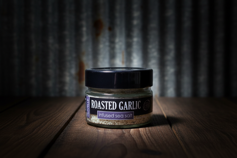 Jar of roasted garlic infused sea salt on a wooden surface with a rustic background