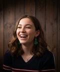 Woman, wearing Christmas tree earrings, laughing with a wooden panel background