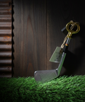 Golf club with a key and dollar bill on grass next to a wooden surface
