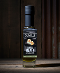 Bottle of Olivelle Vanilla Maple infused olive oil on a wooden surface with a dark background