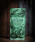 Olivelle Sicilian Seasoning Salt packaging on a wooden surface with a dark background