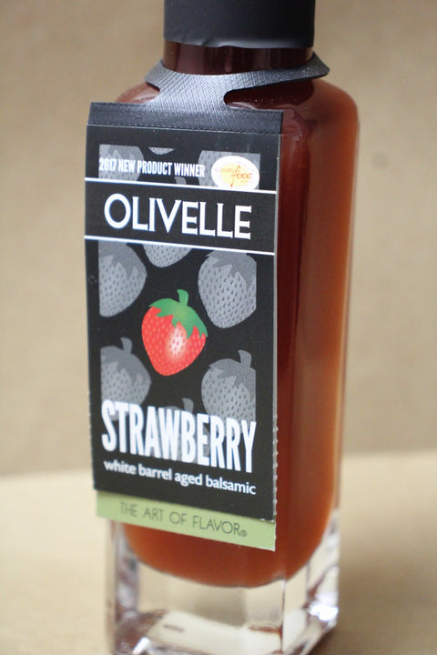 Bottle of Olivelle strawberry white barrel aged balsamic on a beige background