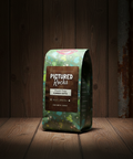Coffee bag labeled 'Pictured Rocks' on a wooden surface with a dark background