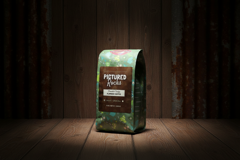 Coffee bag labeled 'Pictured Rocks' on a wooden surface with a dark background