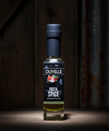 Bottle of Olavelle Fiesta Spice oil on a wooden surface with a dark background