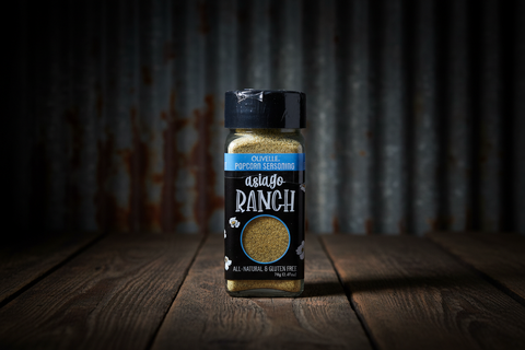 Shaker of asiago ranch seasoning on a wooden surface with a dark background