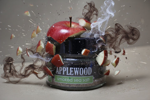 Applewood smoked sea salt container with apples and smoke effects on a neutral background