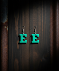 Green letter 'E' earrings on a dark wooden background