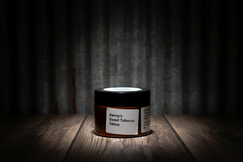 Jar of 'Kenny's Sweet Tobacco Tallow' on a wooden surface with a dark background